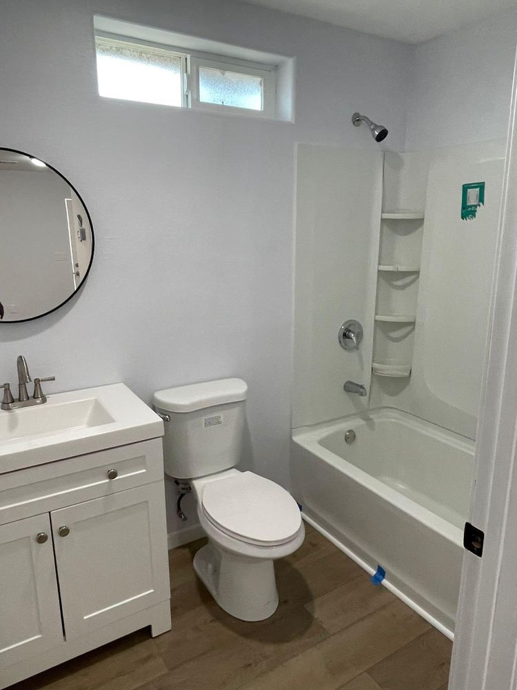 A bathroom with a toilet , sink , bathtub and mirror.