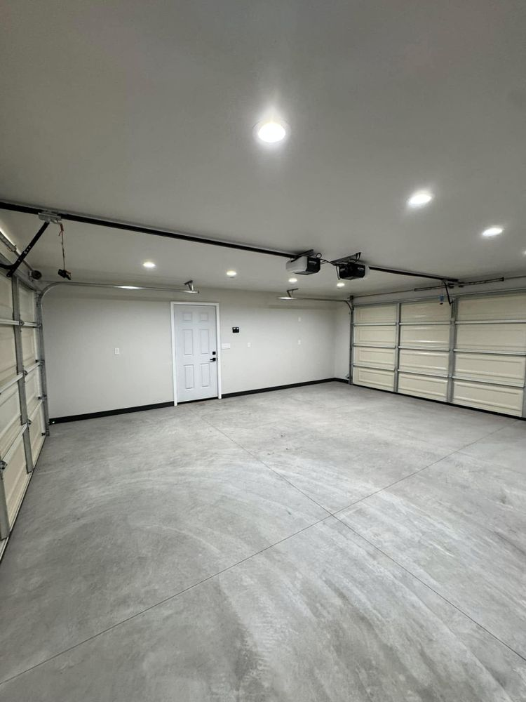 An empty garage with a garage door open and a door.