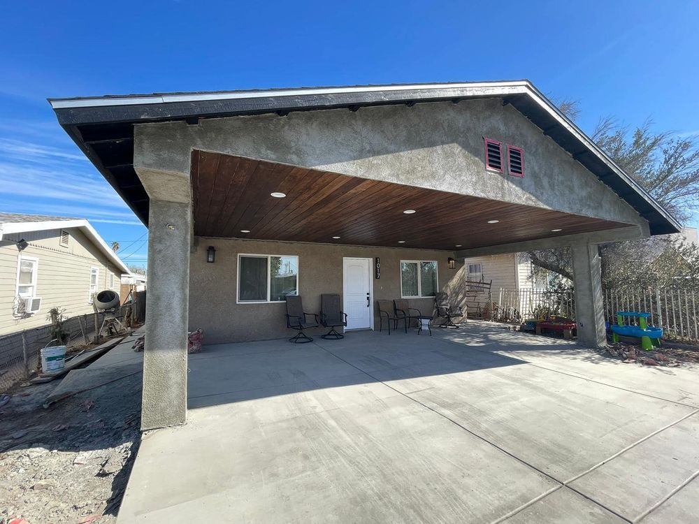 A house with a carport and a patio in front of it.