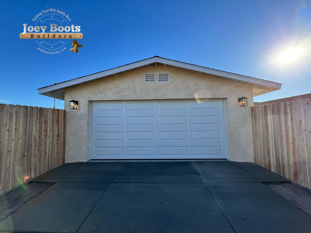 A white garage door is sitting next to a wooden fence.
