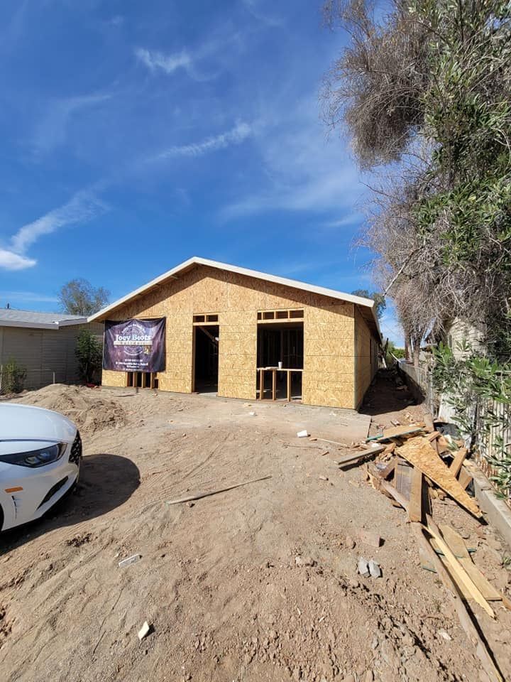 A car is parked in front of a house under construction.