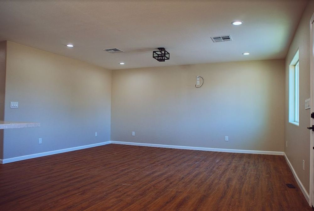 A large empty room with hardwood floors and a ceiling fan.