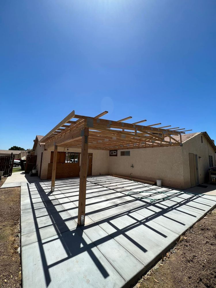 A house with a wooden pergola over a concrete driveway.