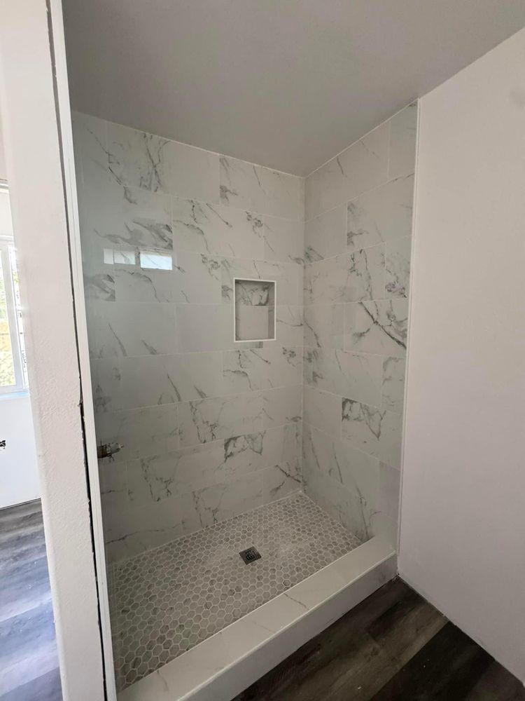 A bathroom with a walk in shower and a marble tiled wall.