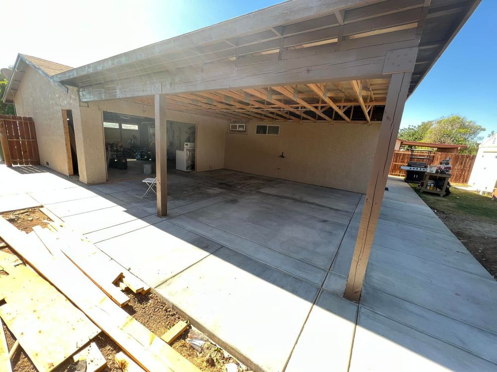 A garage under construction with a wooden roof and a concrete walkway.