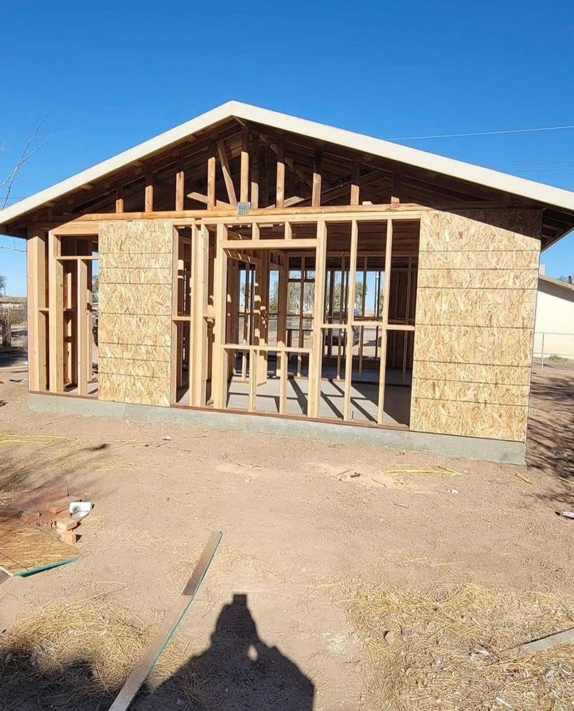 A house is being built in the middle of a dirt field.