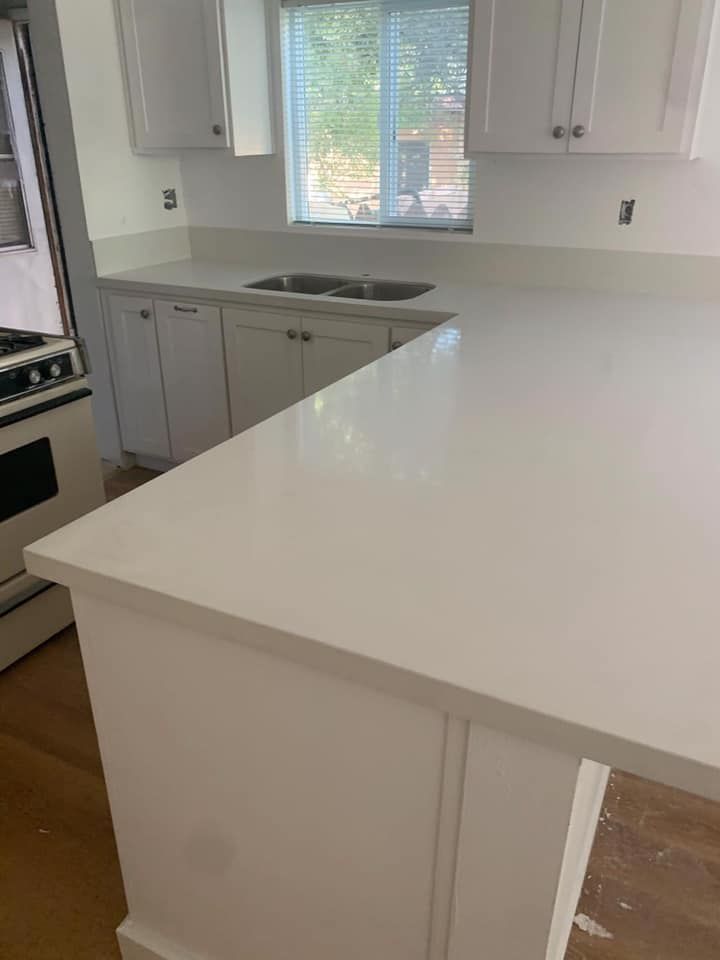A kitchen with white cabinets and a white counter top.