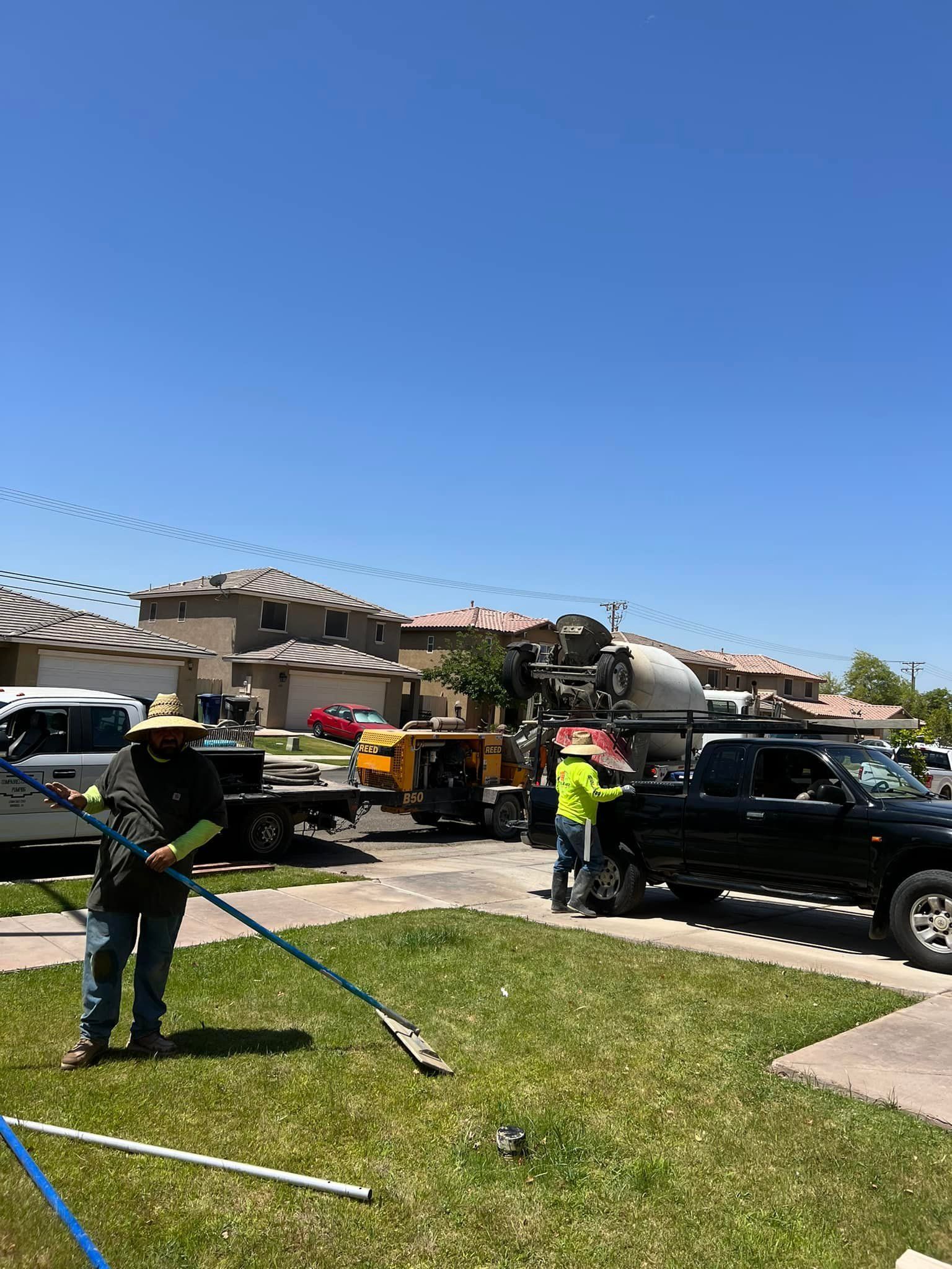 A man is standing in the grass with a hose in front of a truck.