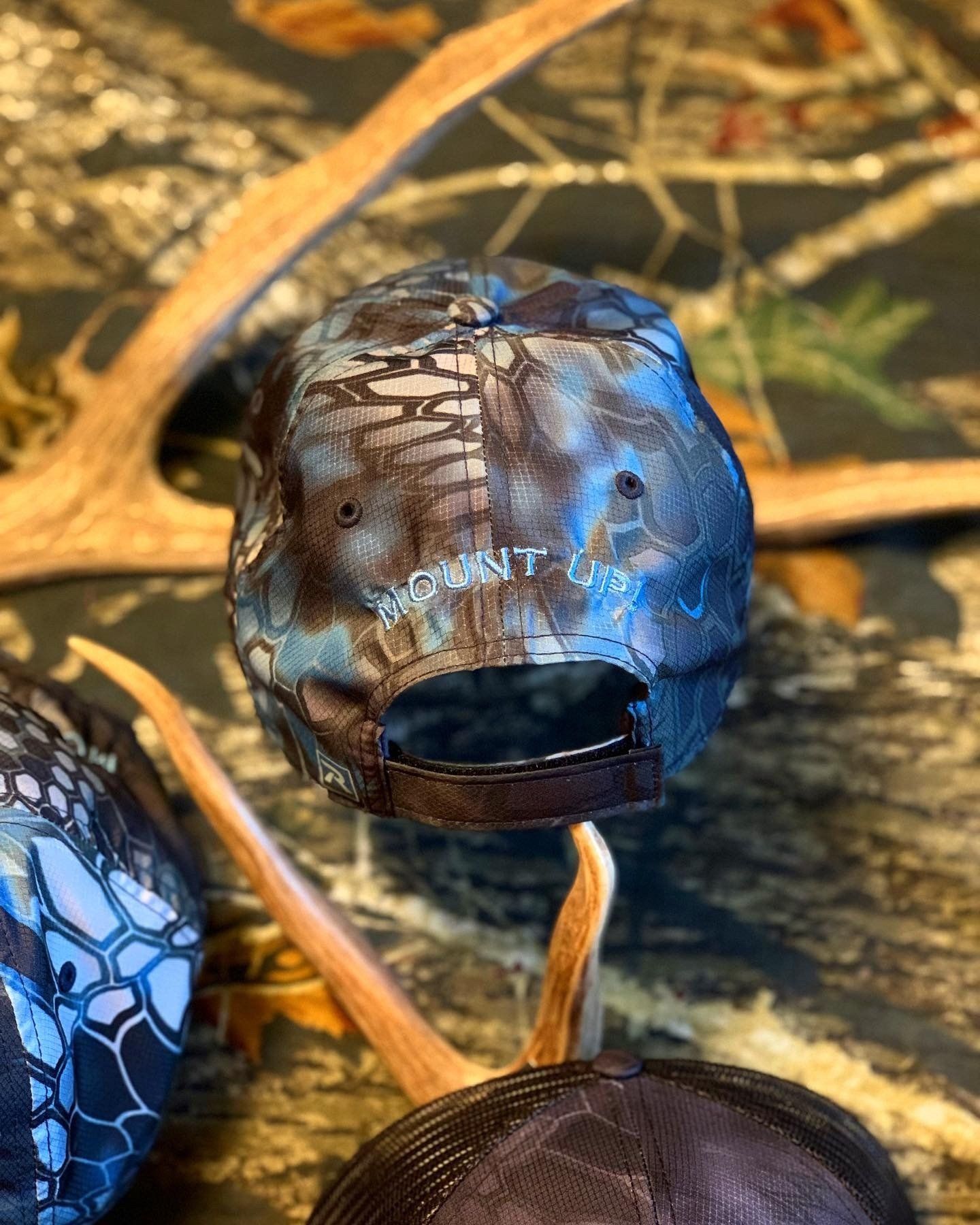 A baseball cap is sitting on a table next to antlers.