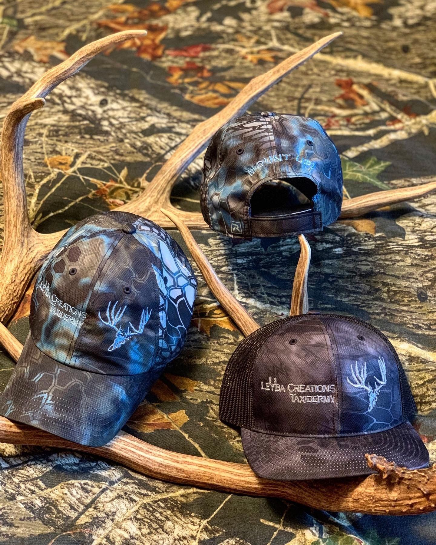 Three hats are sitting on top of antlers on a table.