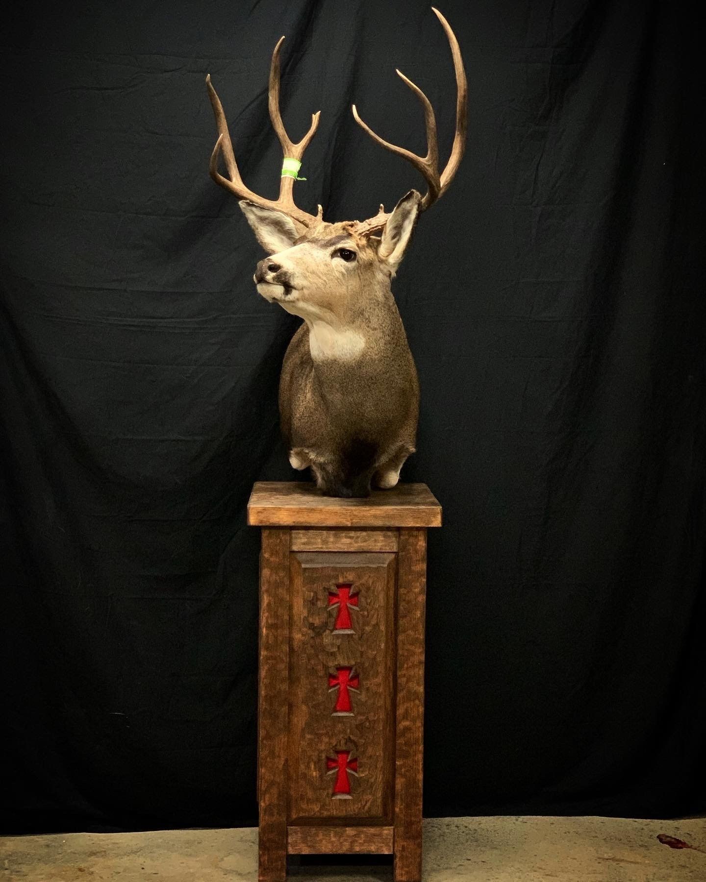 A deer is standing on a wooden pedestal with three crosses on it