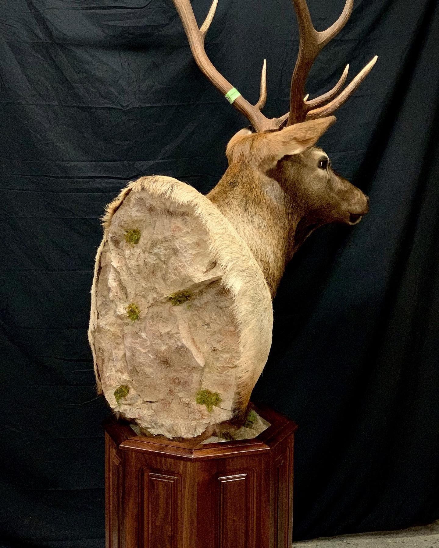 A statue of a deer on a wooden pedestal