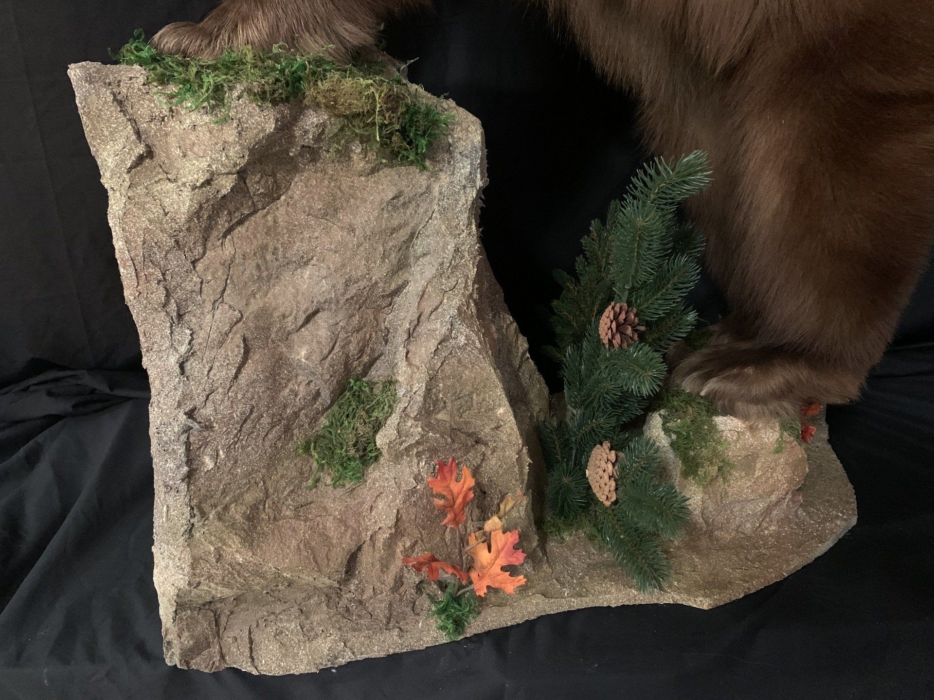 A stuffed brown bear is sitting on top of a rock.
