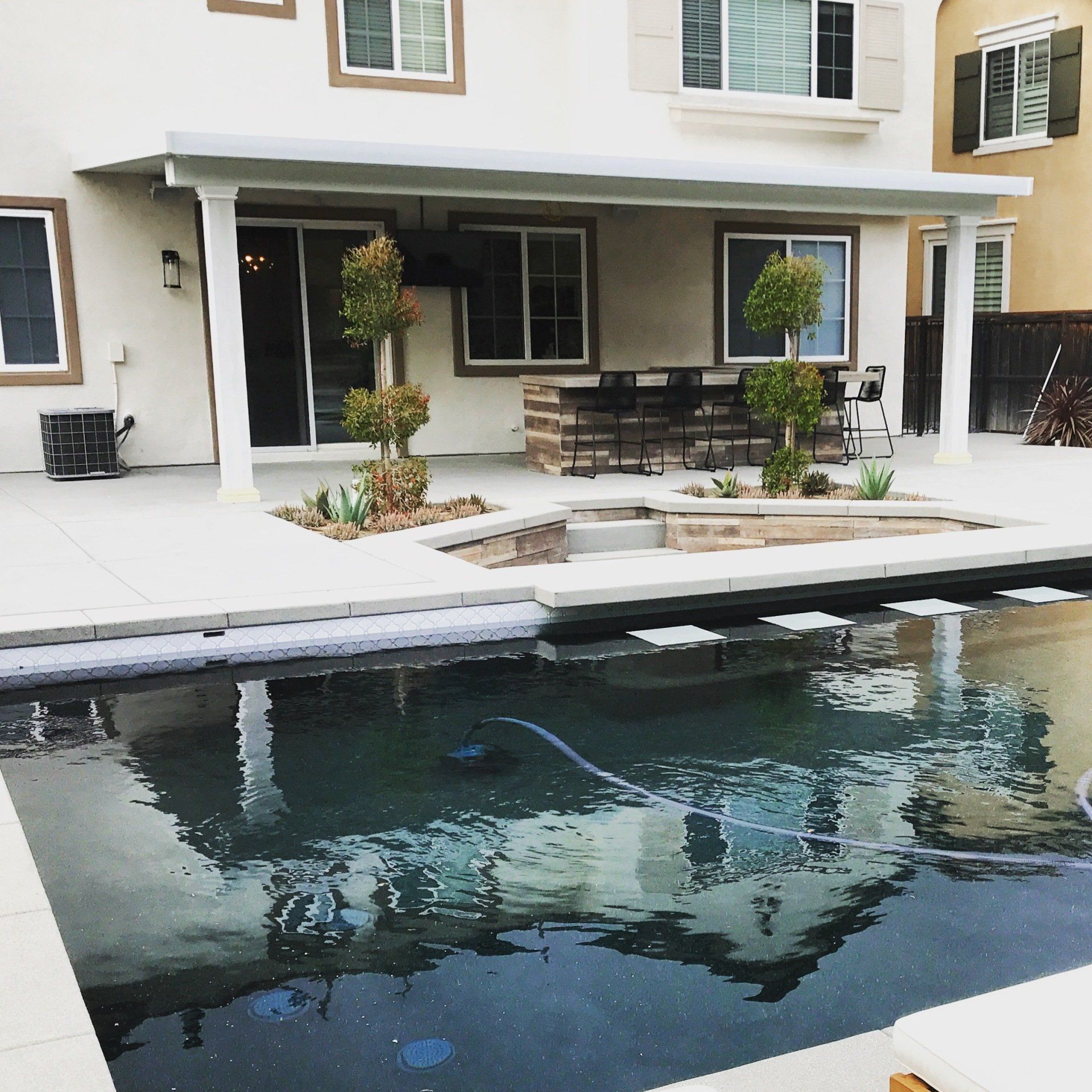 A white house with a large swimming pool in front of it