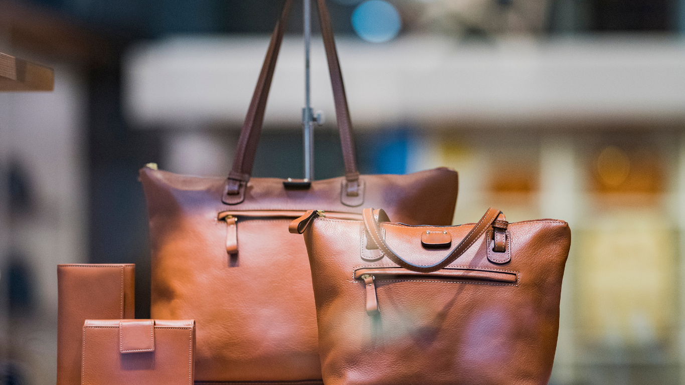 Leather handbags and wallets in a store display. Brown with zippers and buckles.
