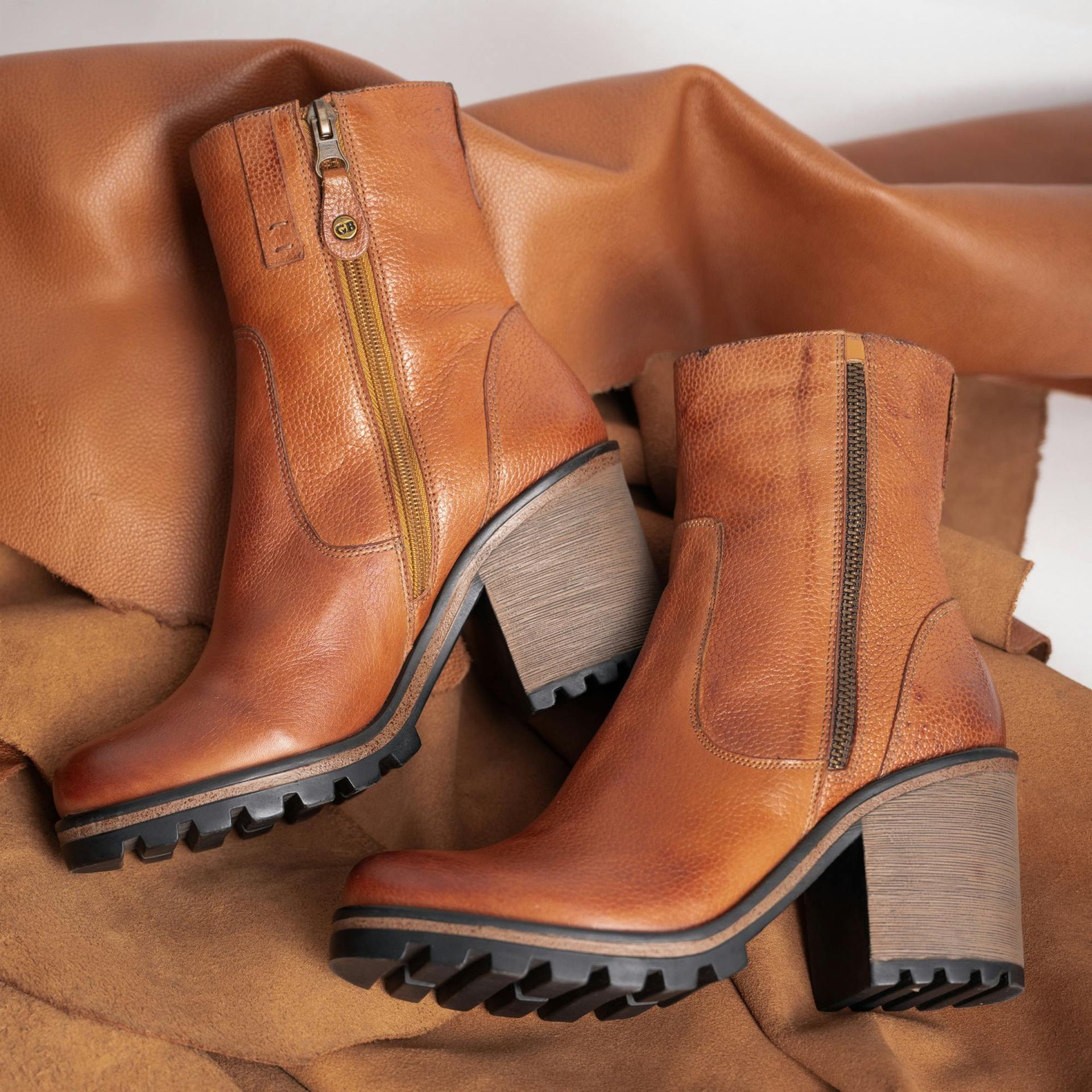 Brown leather ankle boots with chunky heels and side zippers.