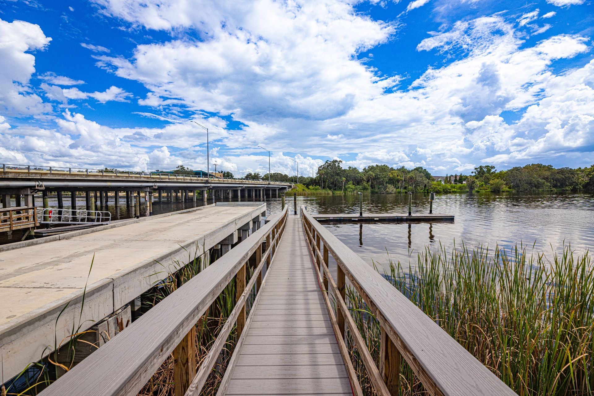 A wooden walkway leading to a lake with a bridge in the background at Riverview Marina