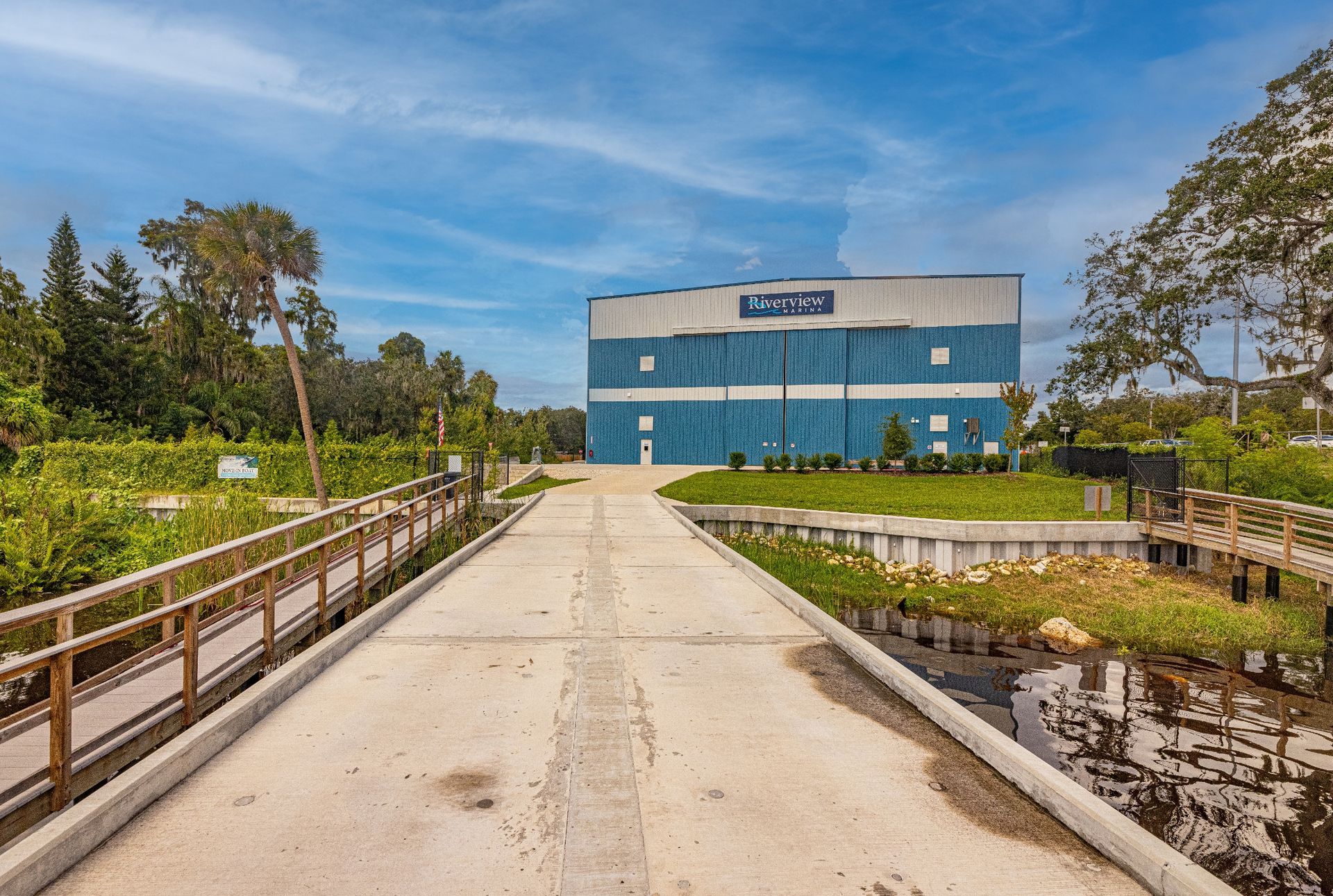 A large blue and white Riverview Marina building is sitting next to a body of water.