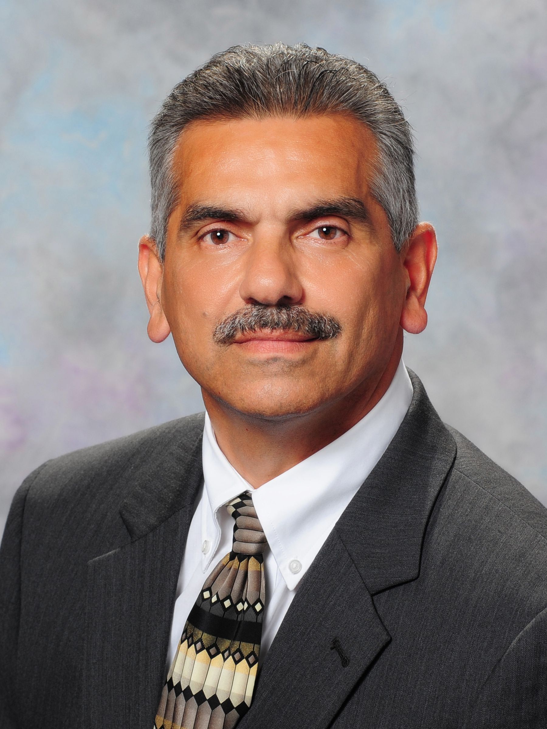 A man with a mustache is wearing a suit and tie