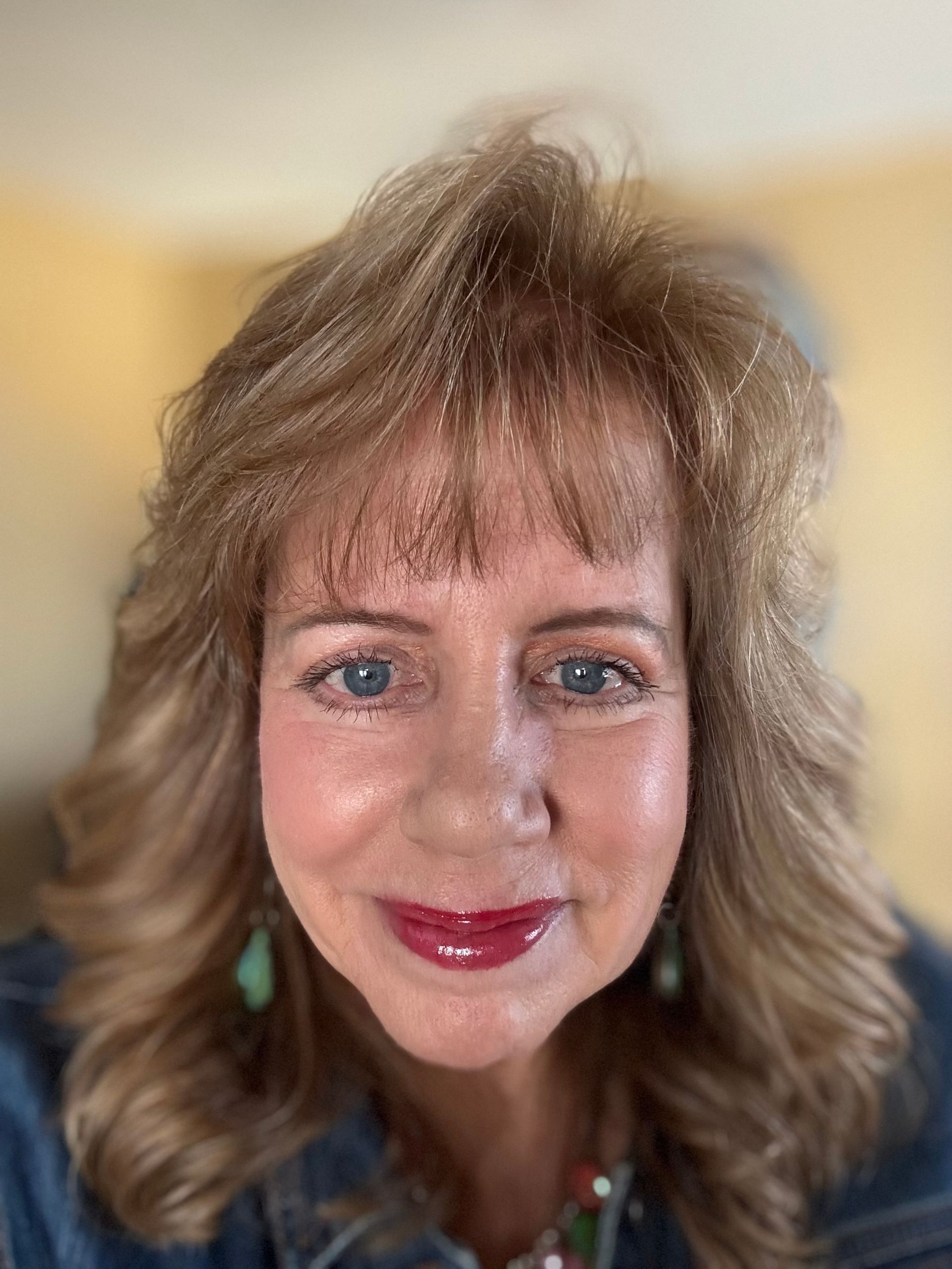 A woman with long hair and blue eyes is smiling for the camera.