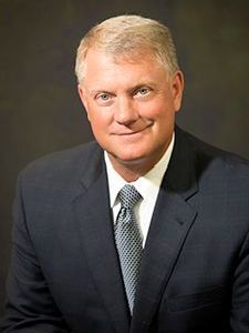 A man in a suit and tie is smiling for the camera.