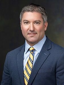 A man in a suit and tie is smiling for the camera.