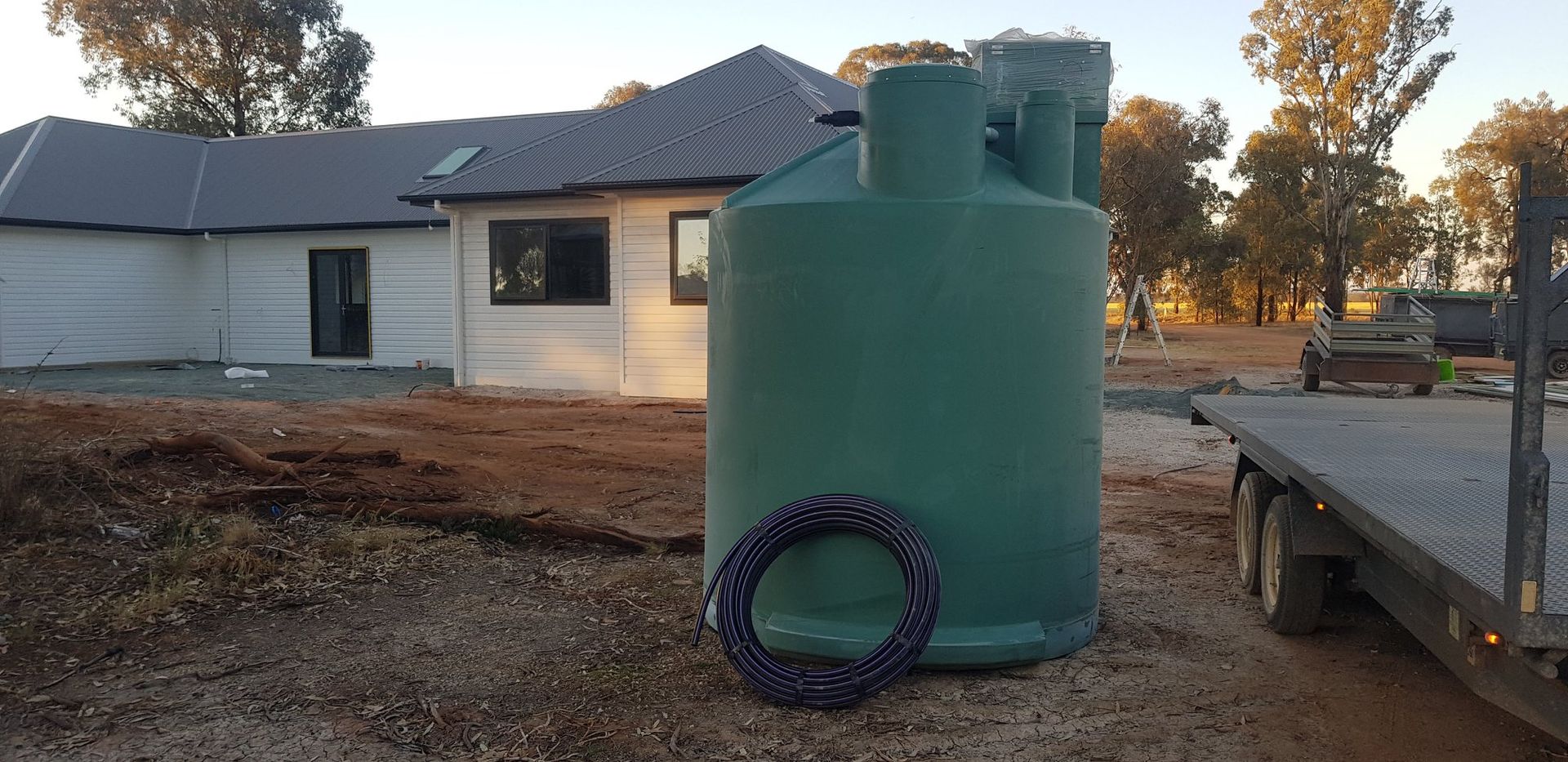 A green water tank in front of a house under construction; a trailer sits to the right. — Mi Plumber Wagga Wagga in Lake Albert, NSW