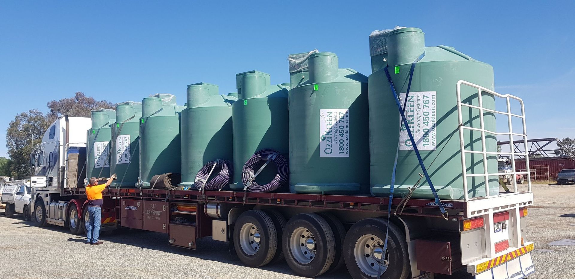 A Truck Carrying Several Large Green Water Tanks — Mi Plumber Wagga Wagga in Lake Albert, NSW