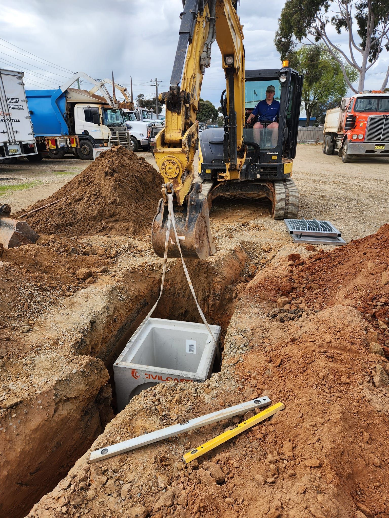 Excavator Lifting a Concrete Box From a Trench at a Construction Site — Mi Plumber Wagga Wagga in Lake Albert, NSW