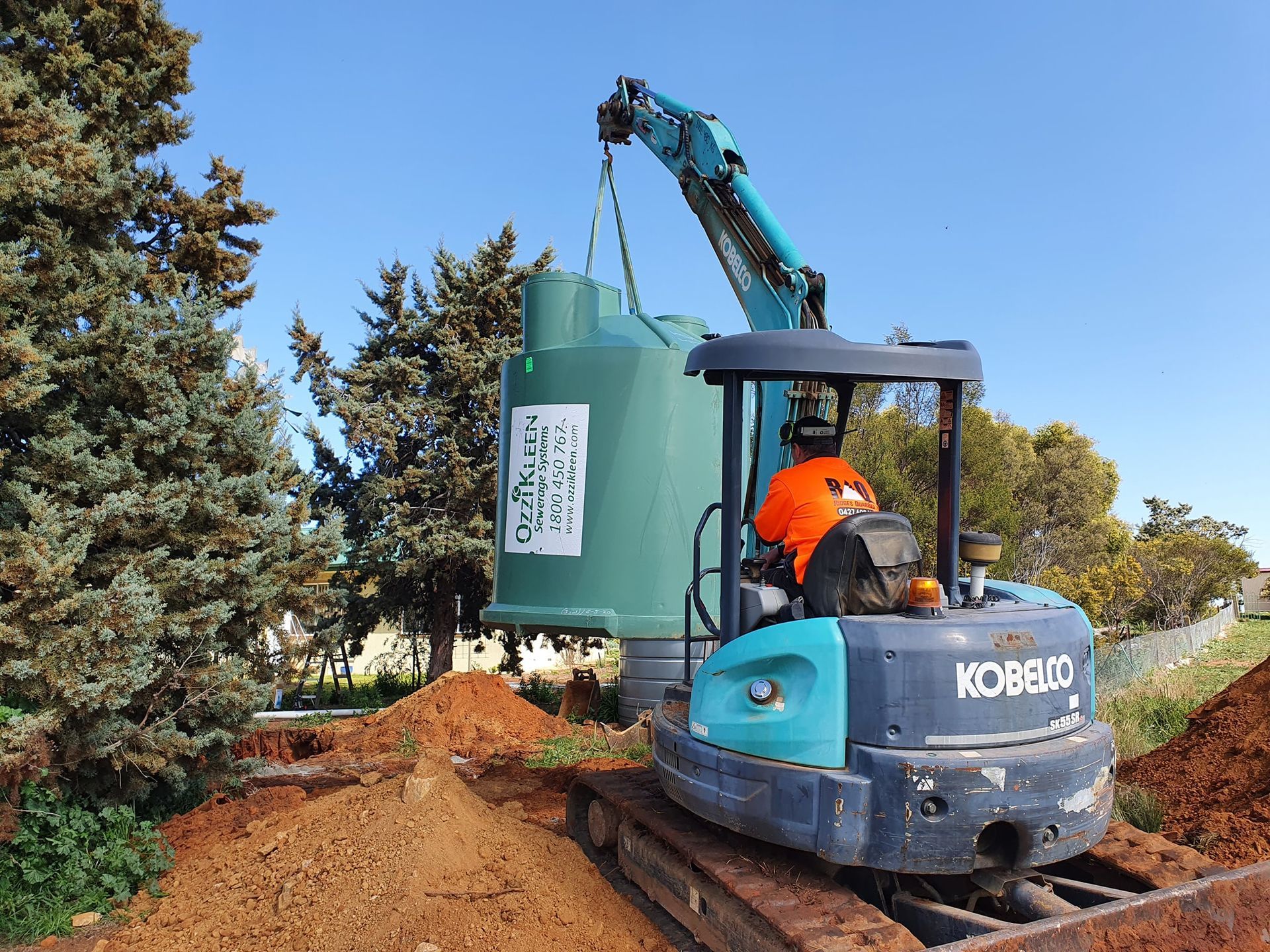 Mini Excavator Lifts a Green Septic Tank — Mi Plumber Wagga Wagga in Lake Albert, NSW