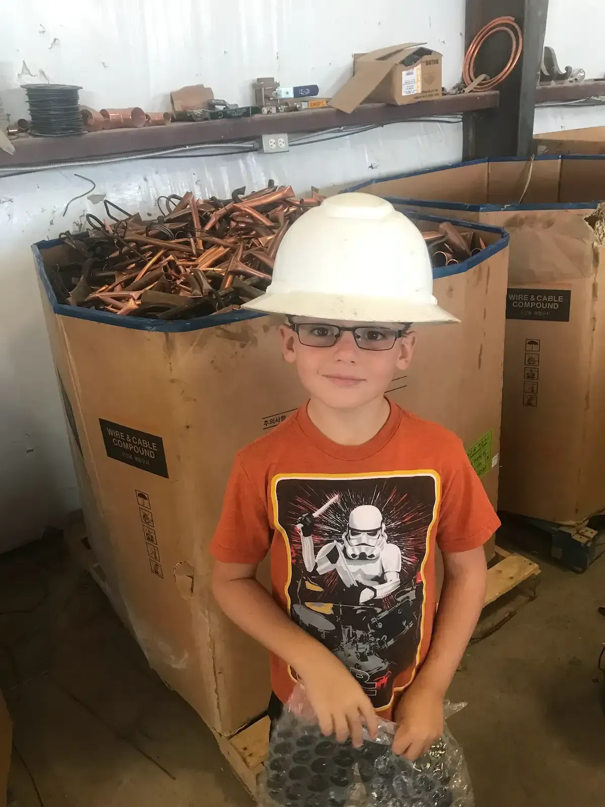 Woman in straw hat smiles, holding wine glass near a lake.