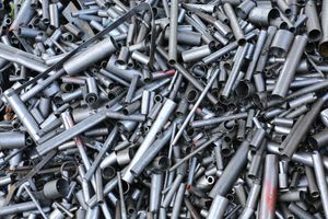 A large, cluttered pile of assorted metal tubes and pipes scattered in a heap, metallic grey in color.