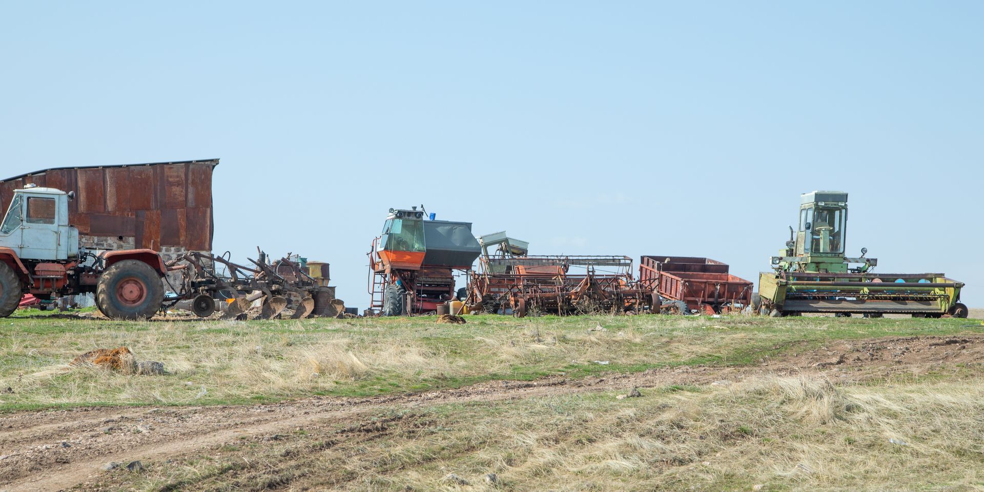 Woman in straw hat smiles, holding wine glass near a lake.