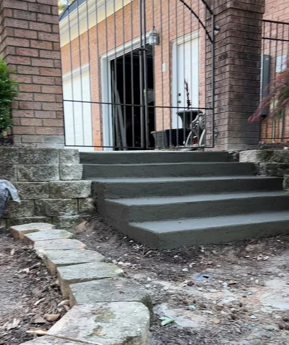 Concrete steps with metal handrails leading to a building entrance. A person is near the glass doors.