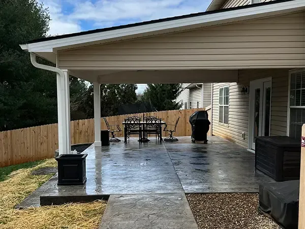 Covered patio with dining set, grill, and planters.