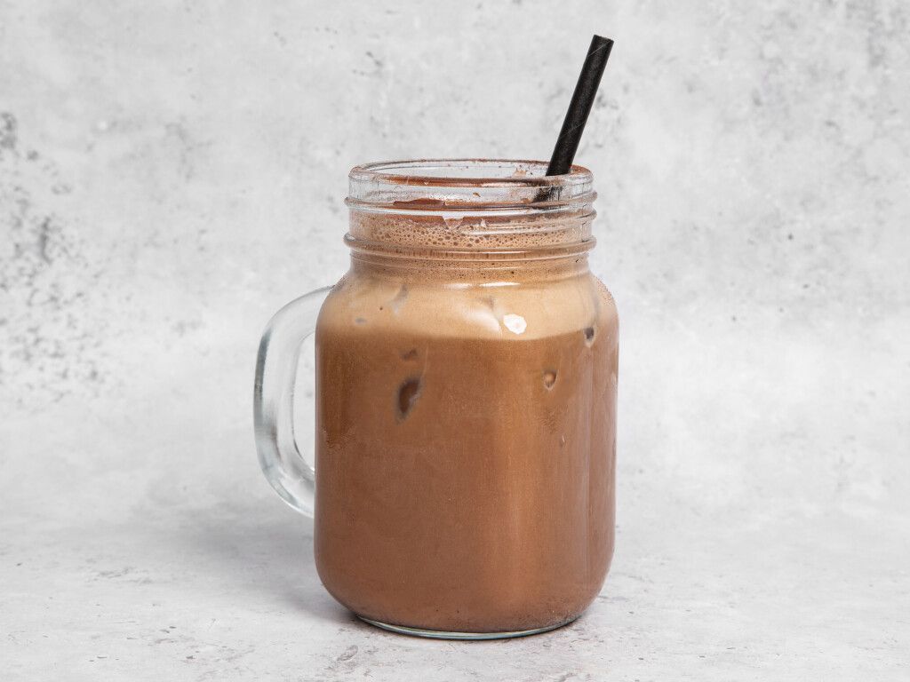 Iced chocolate drink in mason jar with a black straw.