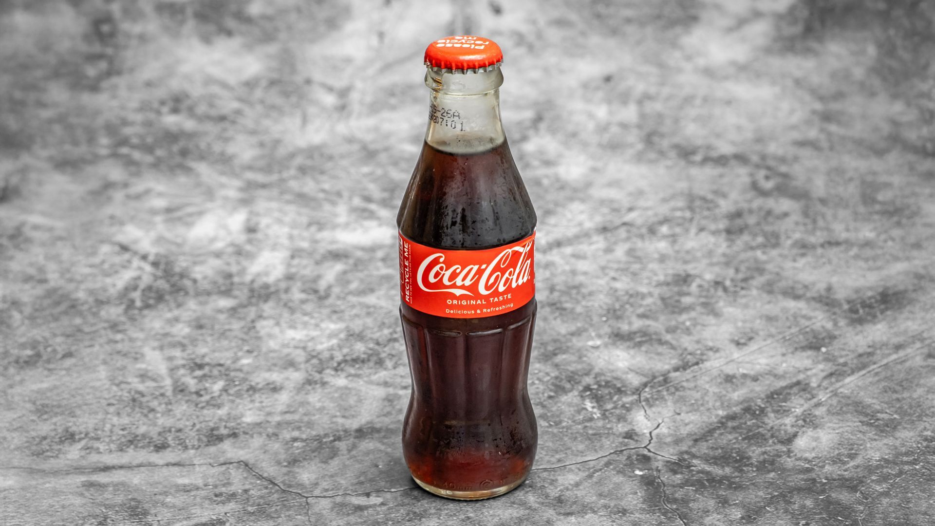 Coca-Cola bottle with a red label and cap, on a gray background.