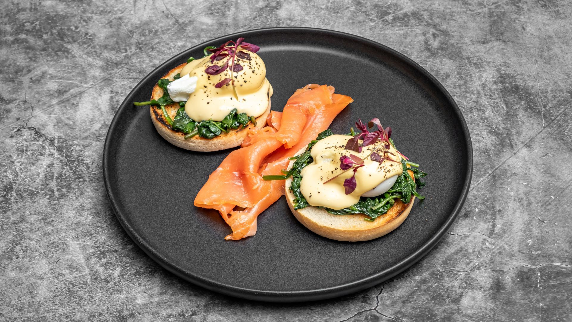 Eggs Benedict with smoked salmon on a black plate.