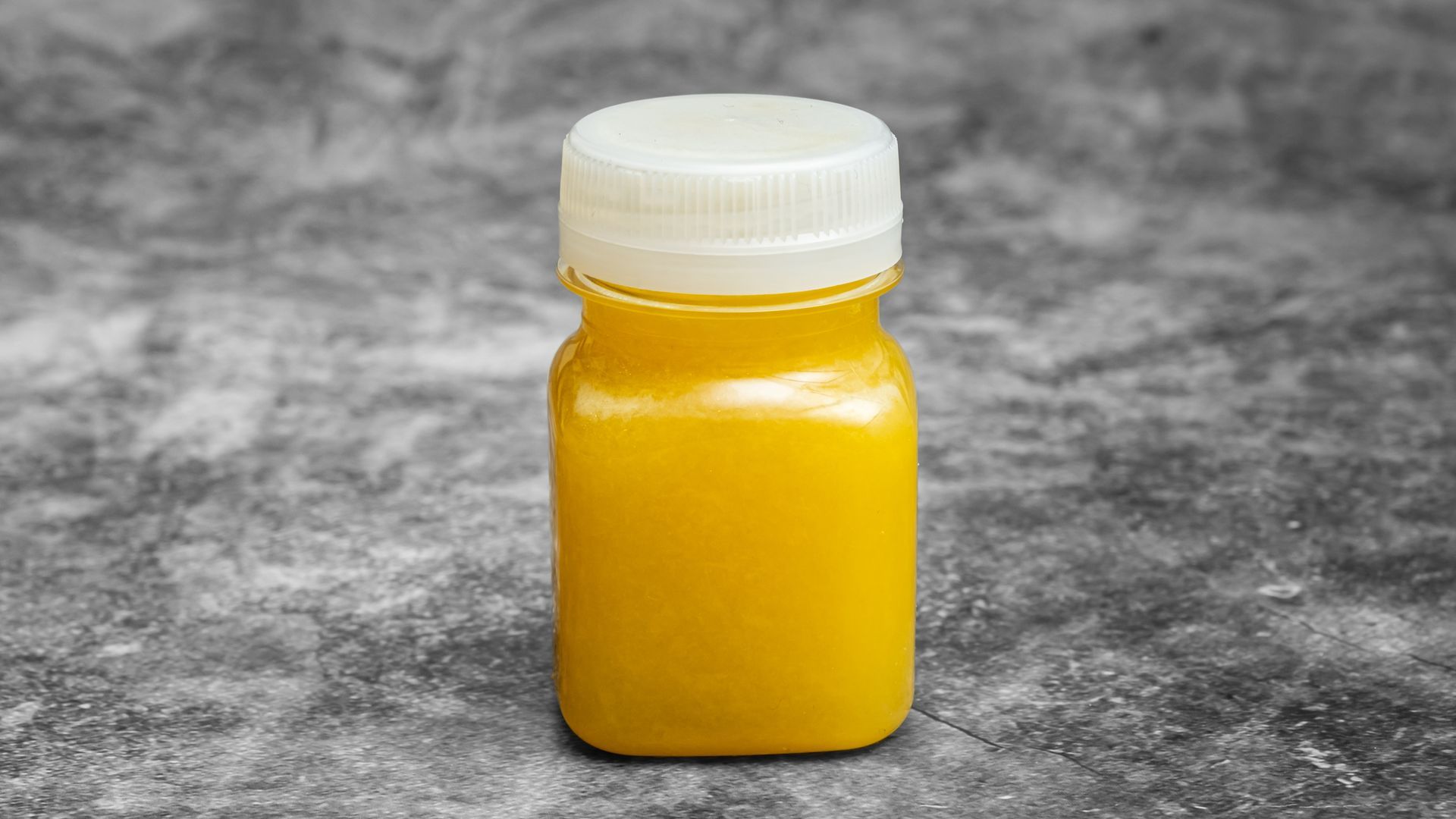 Yellow liquid-filled bottle with a white cap on a gray background.
