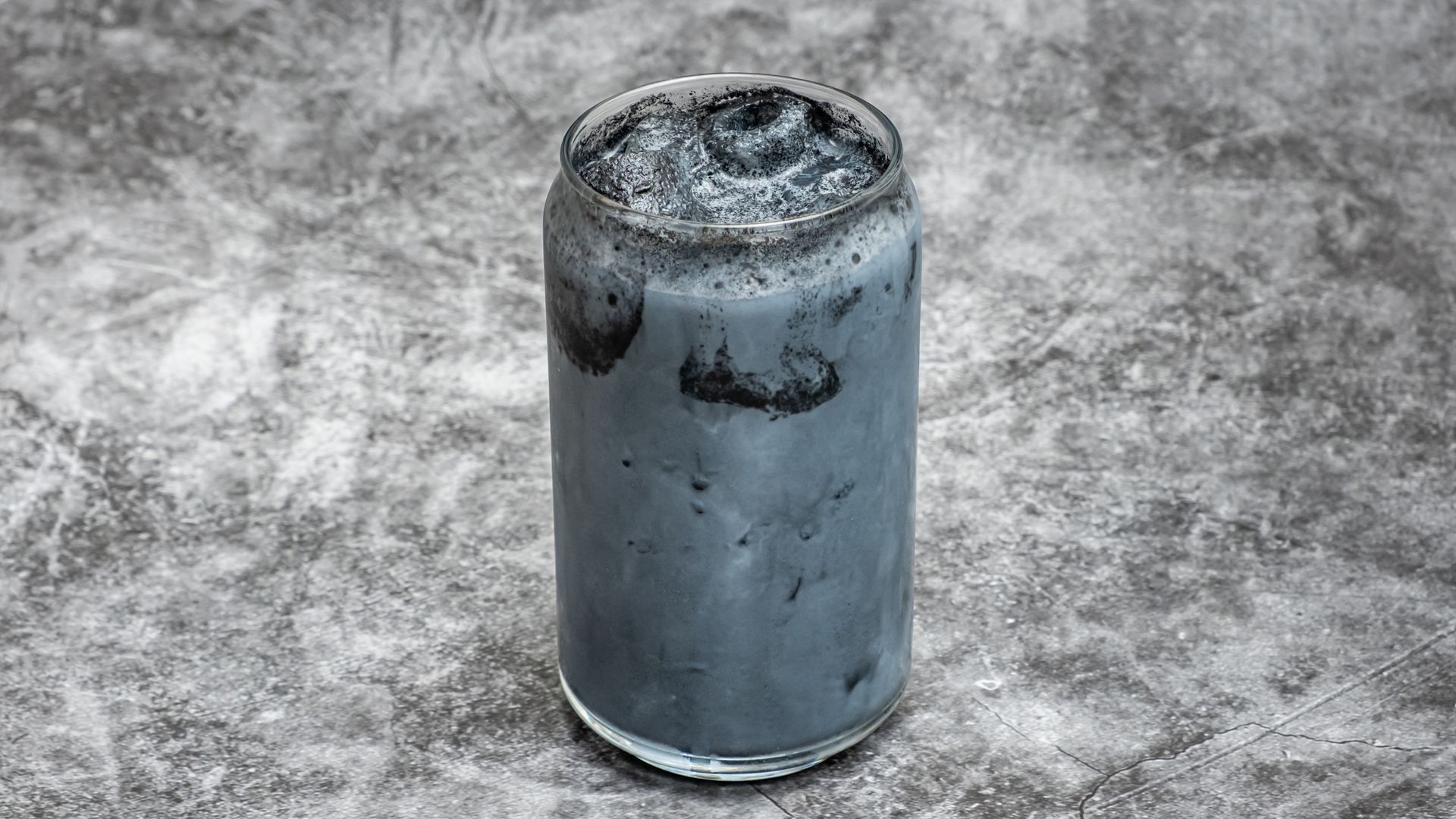 Black beverage in a glass on a gray surface.