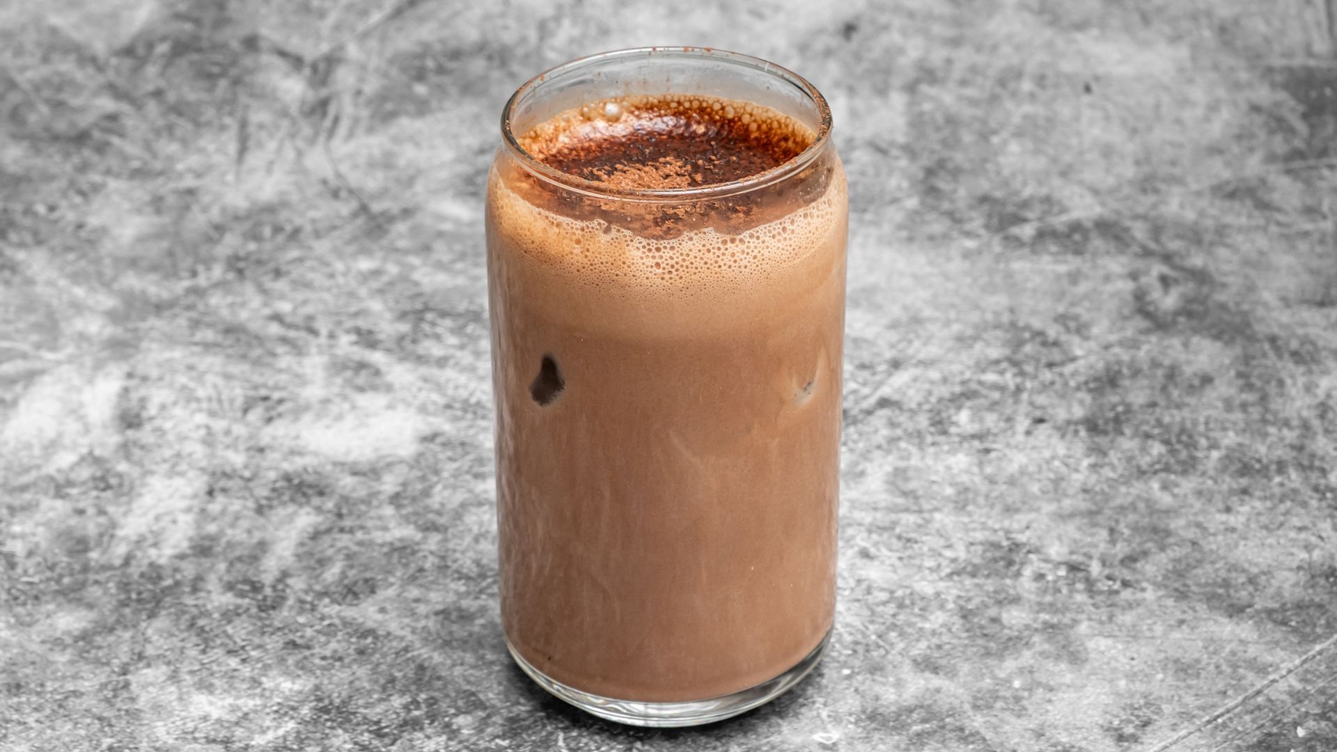 Glass of chocolate milkshake on a gray background.