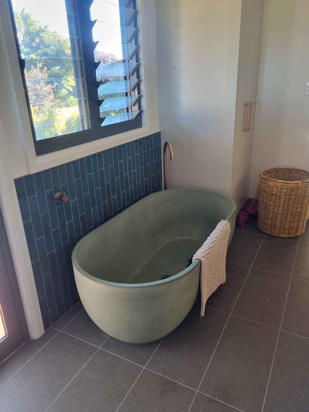 A Green Bathtub Is Sitting in A Bathroom Next to A Window — Origin Plumbing & Gas in Bangalow, NSW