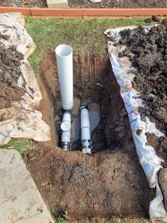 A Couple of Pipes Are Sitting in A Hole in The Ground — Origin Plumbing & Gas in Tuckurimba, NSW