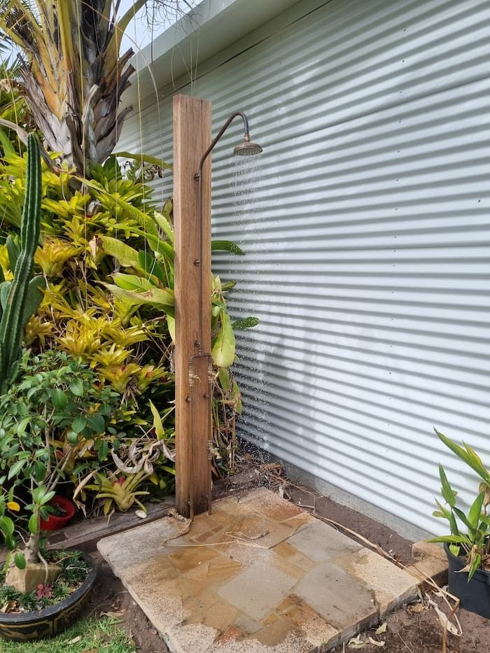 A Wooden Outdoor Shower Is Sitting in The Middle of A Garden — Origin Plumbing & Gas in Tuckurimba, NSW