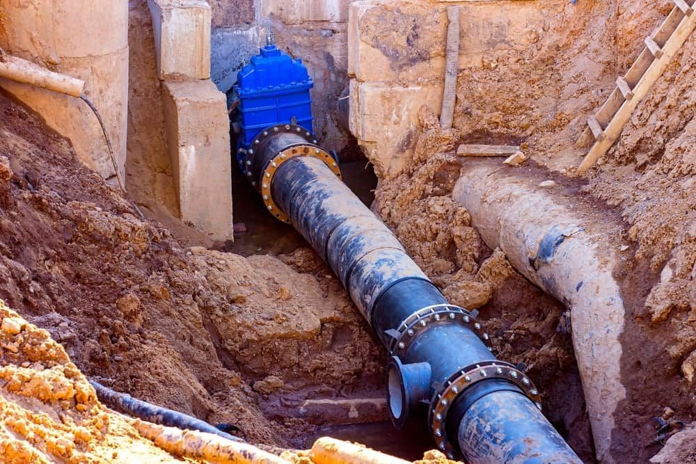 A Blue Pipe Is Going Through a Hole in The Ground — Origin Plumbing & Gas in Tuckurimba, NSW