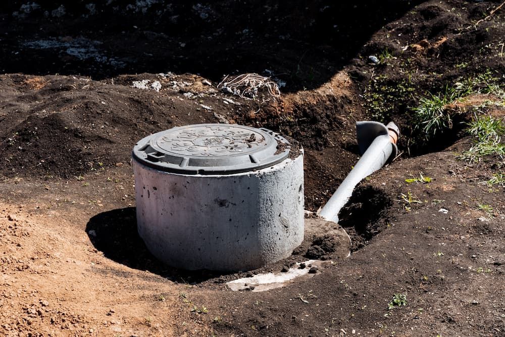 A Concrete Septic Tank Is Sitting in The Dirt Next to A Pipe — Origin Plumbing & Gas in Lennox Head, NSW