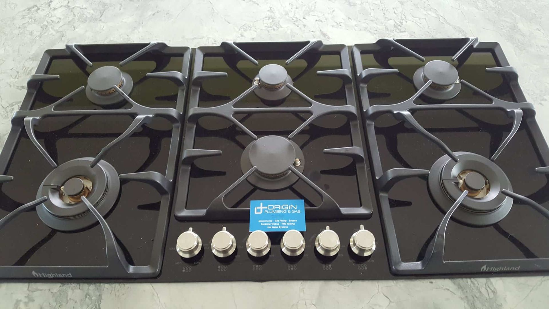 A Black Stove Top with A Blue Label — Origin Plumbing & Gas in Tuckurimba, NSW