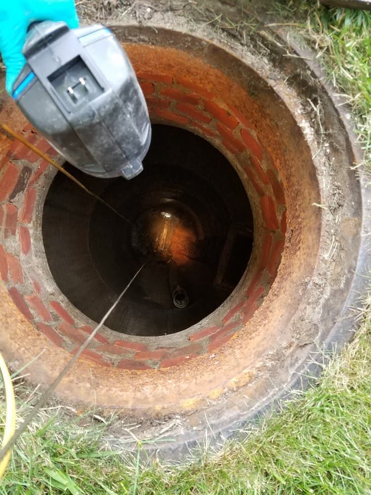 A Person Is Looking Into a Manhole with A Camera — Origin Plumbing & Gas in Tuckurimba, NSW