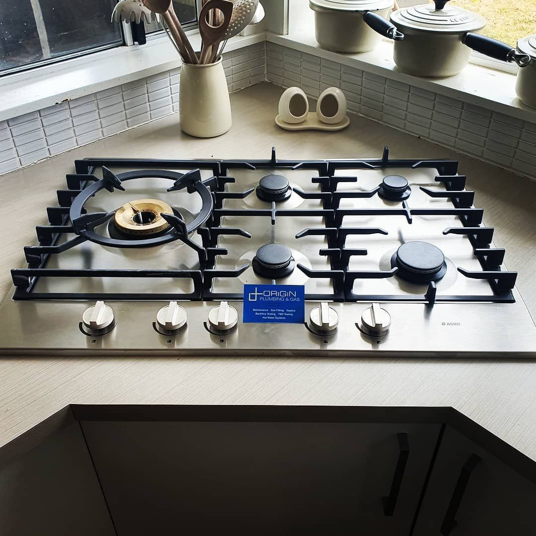A Stainless Steel Stove Top with A Blue Sign on It — Origin Plumbing & Gas in Tuckurimba, NSW