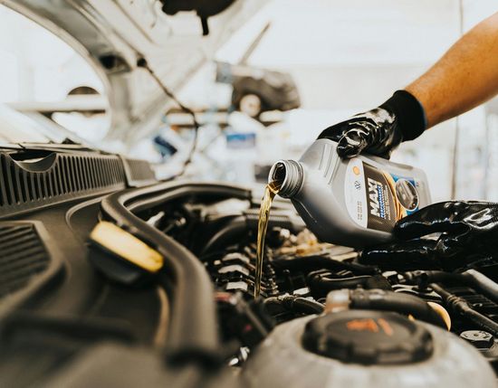 A person is pouring oil into a car engine.